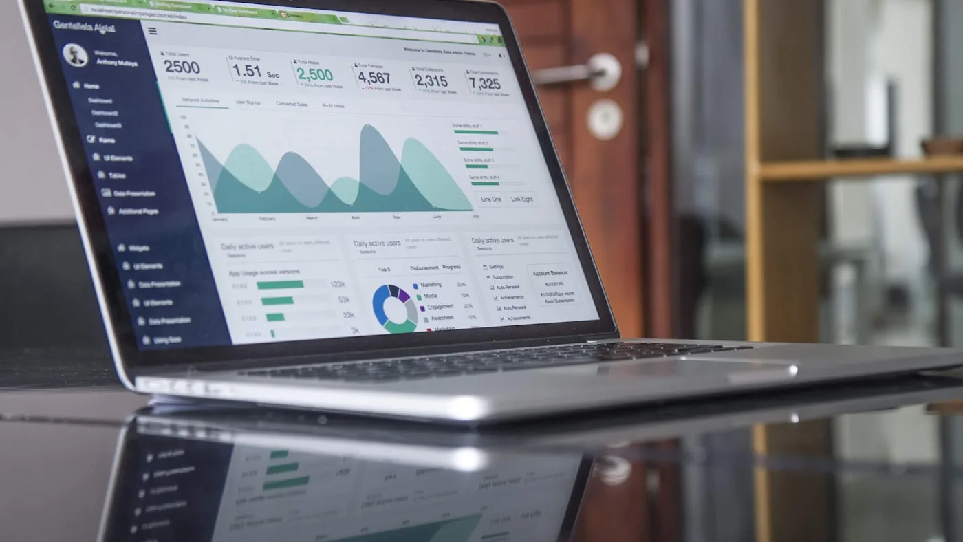 A laptop on a desk showing a marketing analytics dashboard with charts