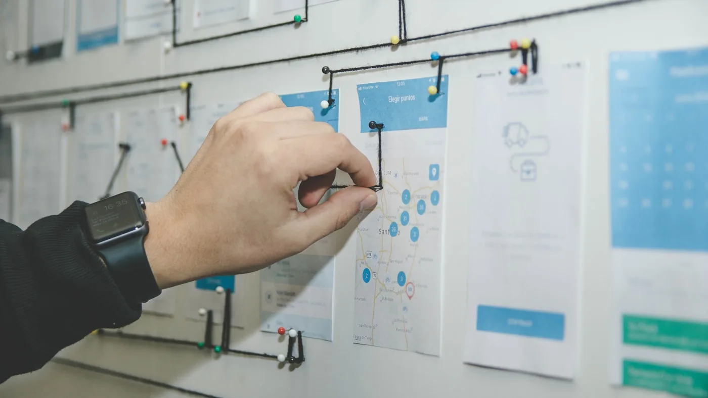 A person arranging colored planning cards on a board while weighing options